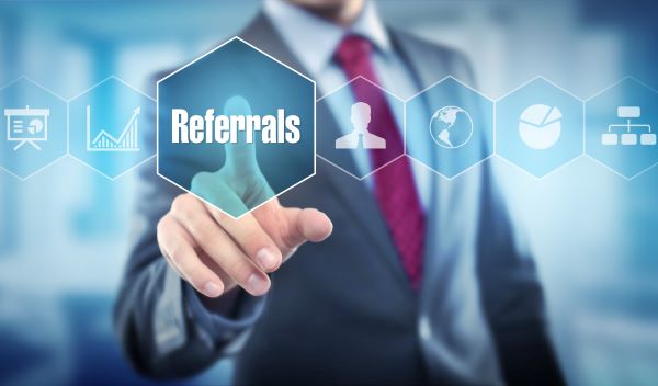 A man in a suit and tie points to the word referrals.